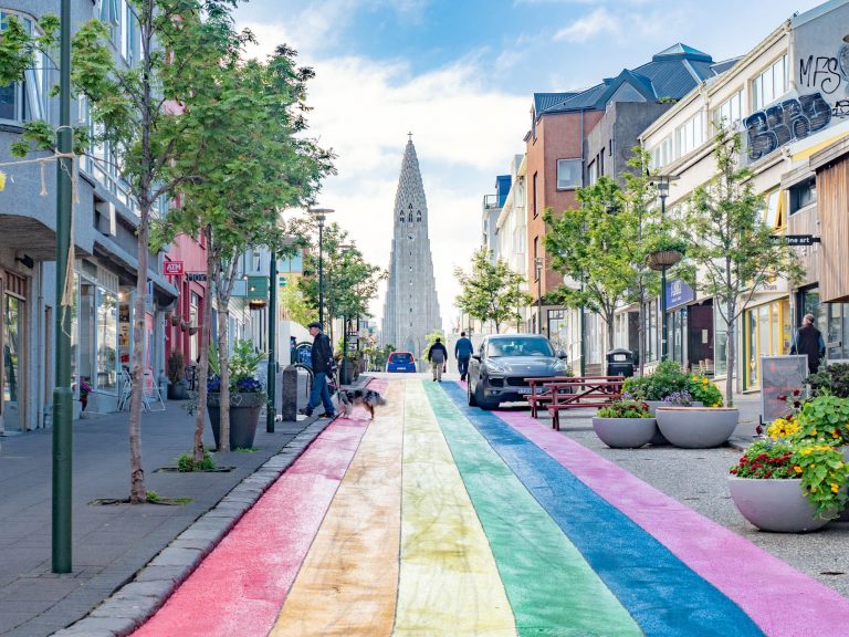 City street painted like a rainbow with a tall church at the end