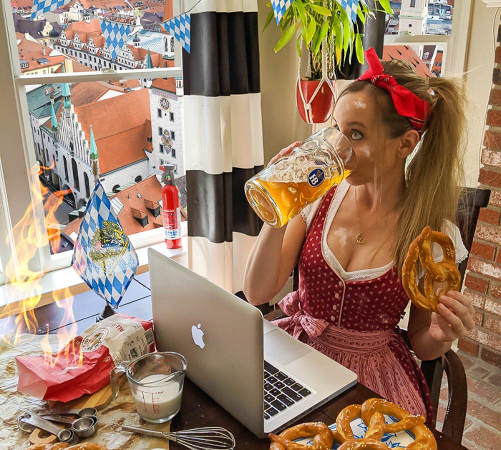 me in a red dirndl eating pretzels and drinking beer in front of a munich backdrop