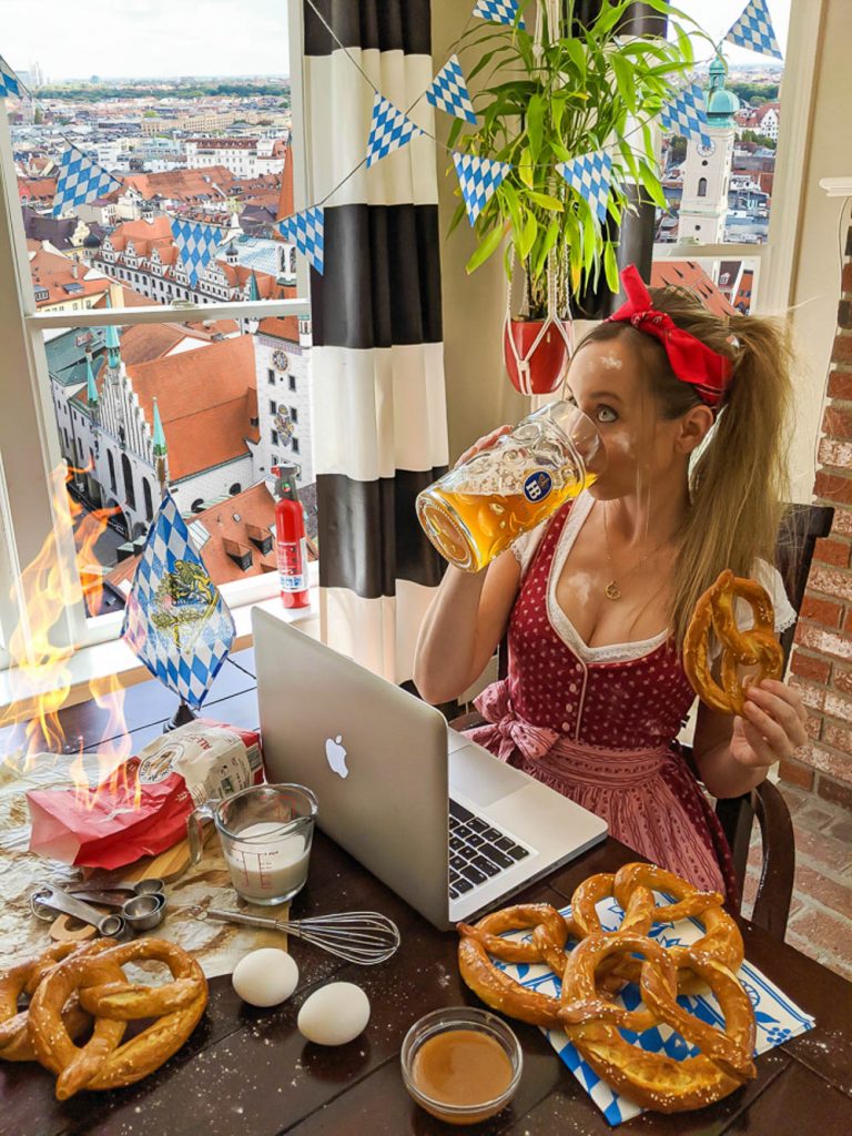 me in a red dirndl eating pretzels and drinking beer in front of a munich backdrop