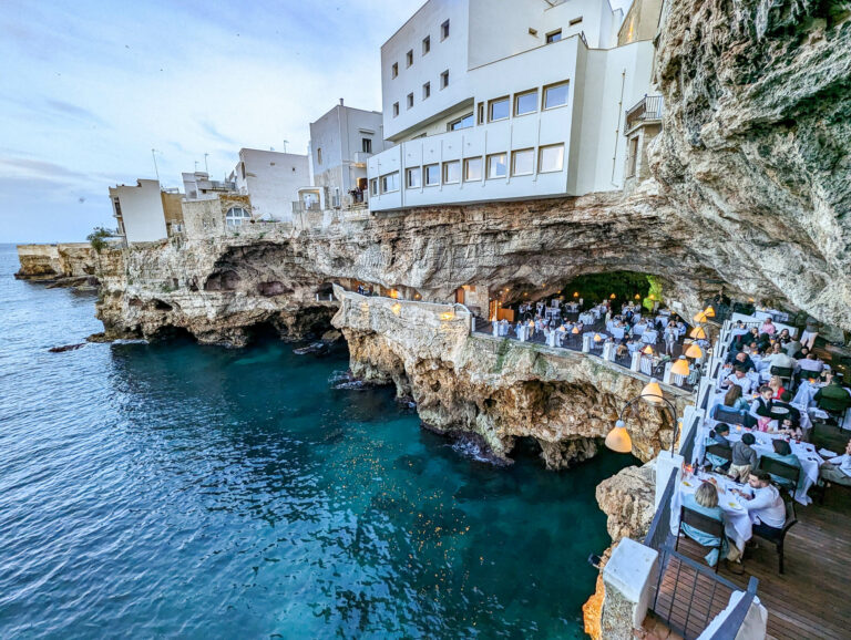 looking down on the tables and sea from above inside the cave during the day