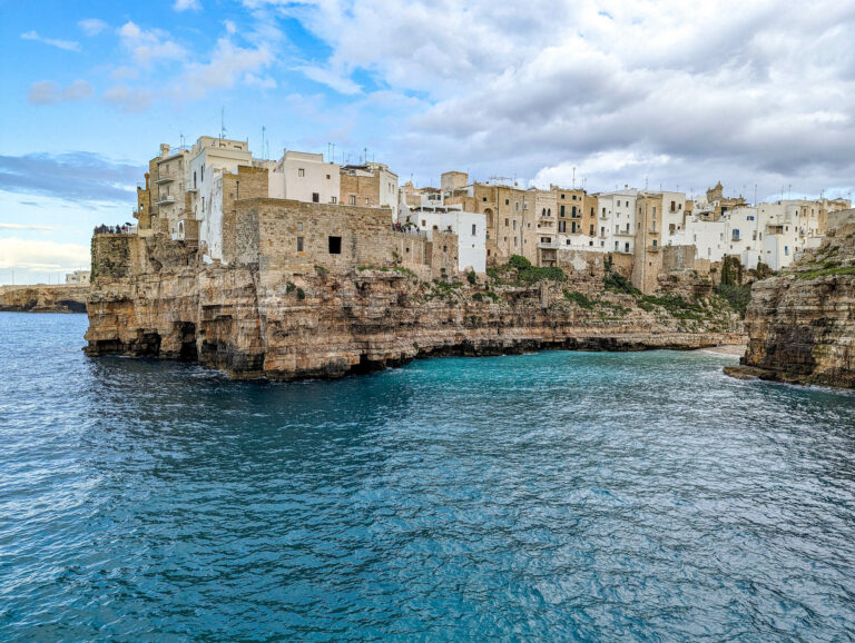 white and tan buildings on a cliff over a turquoise ocean