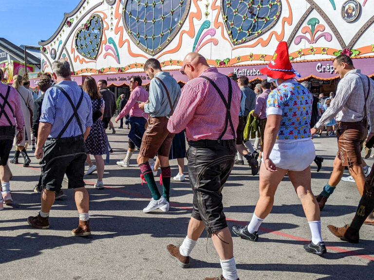 group of men walking through oktoberfest and one of them is wearing a diaper