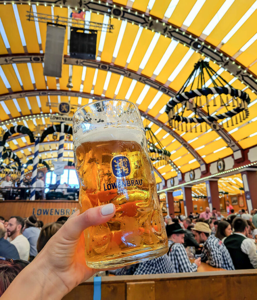 hand holding large beer inside an oktoberfest beer tent