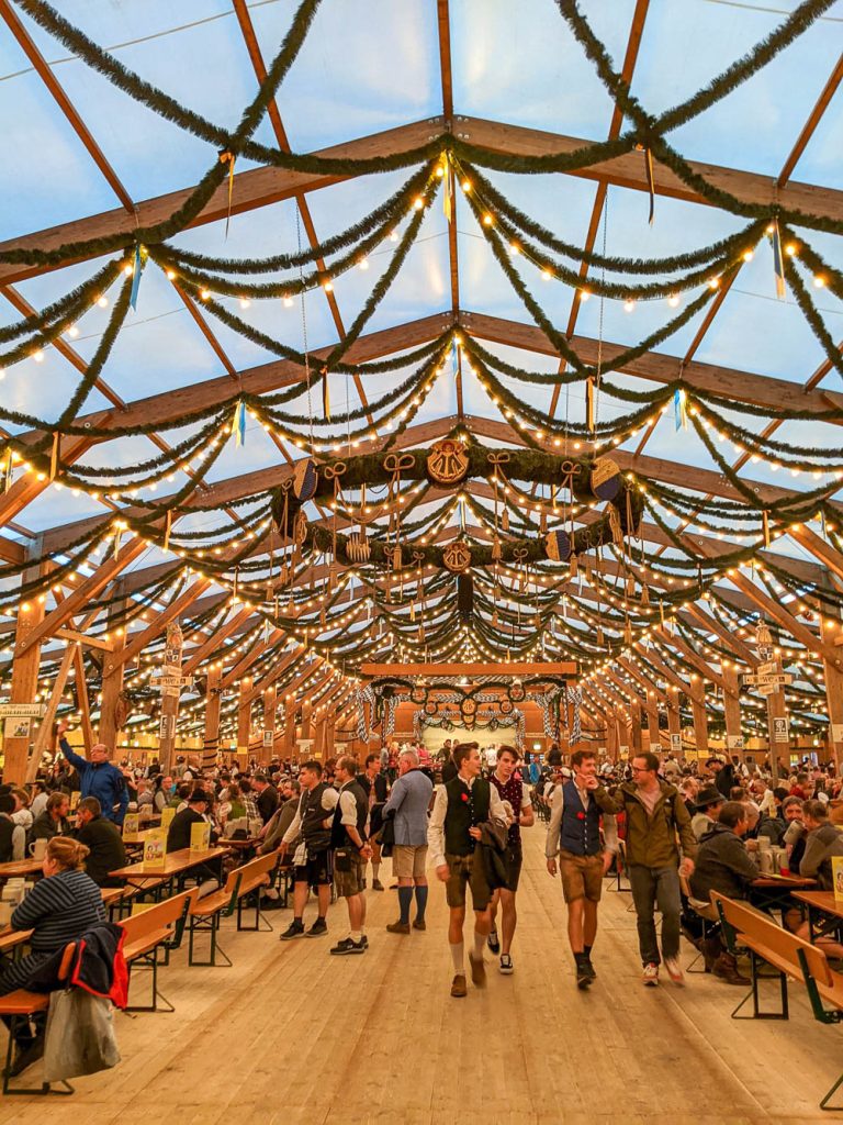 inside an oktoberfest beer tent with lots of lights and pine garland strung across the ceiling