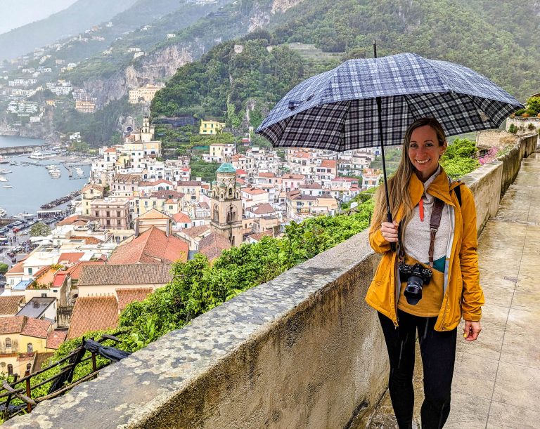 girl in yellow rain jacket over a city lookout holding an umbrella