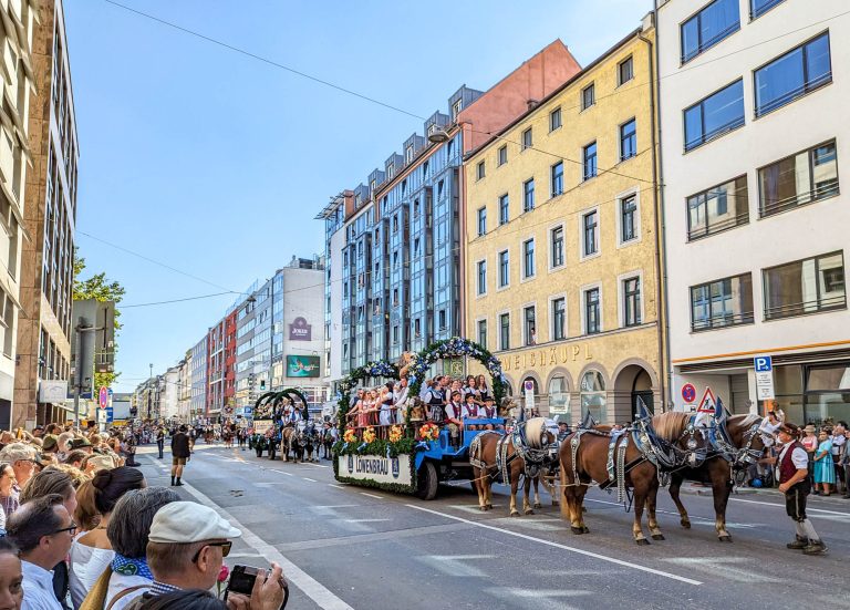 horse-drawn carriage going down a city street lined with people and colorful buildings